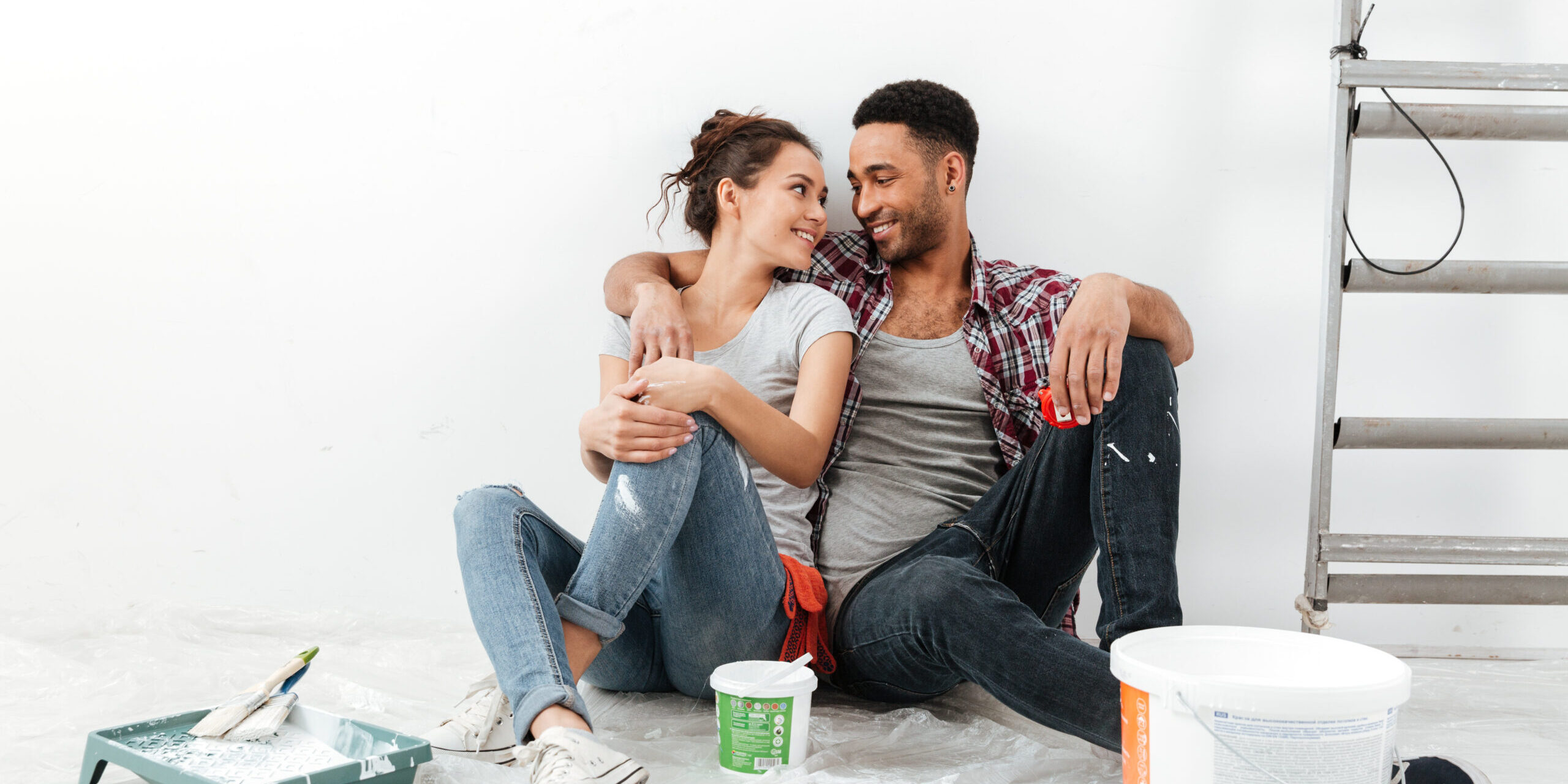 Cheerful multiethnic young couple renovating home and resting