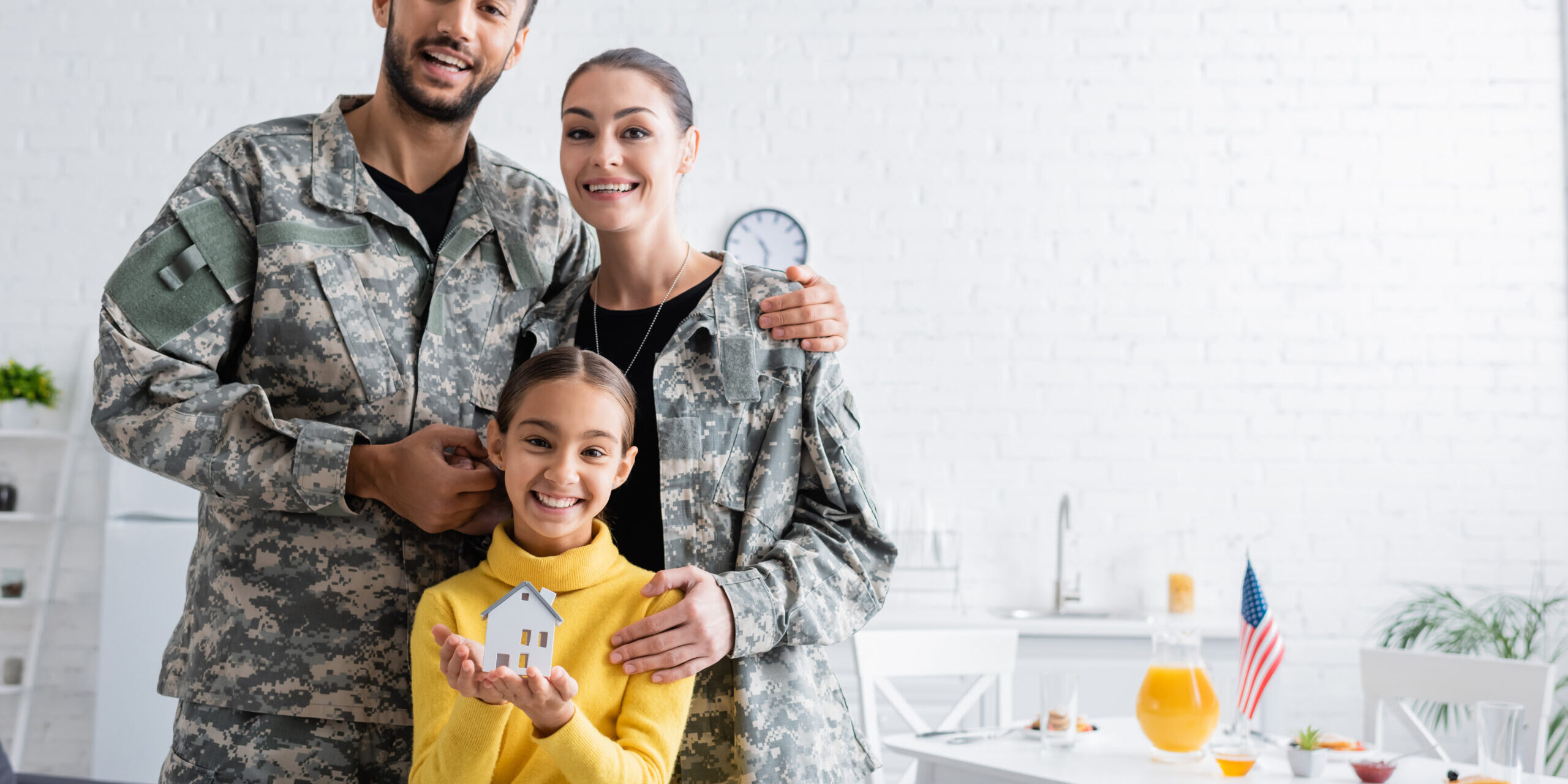 Smiling parents in military uniform standing near daughter with