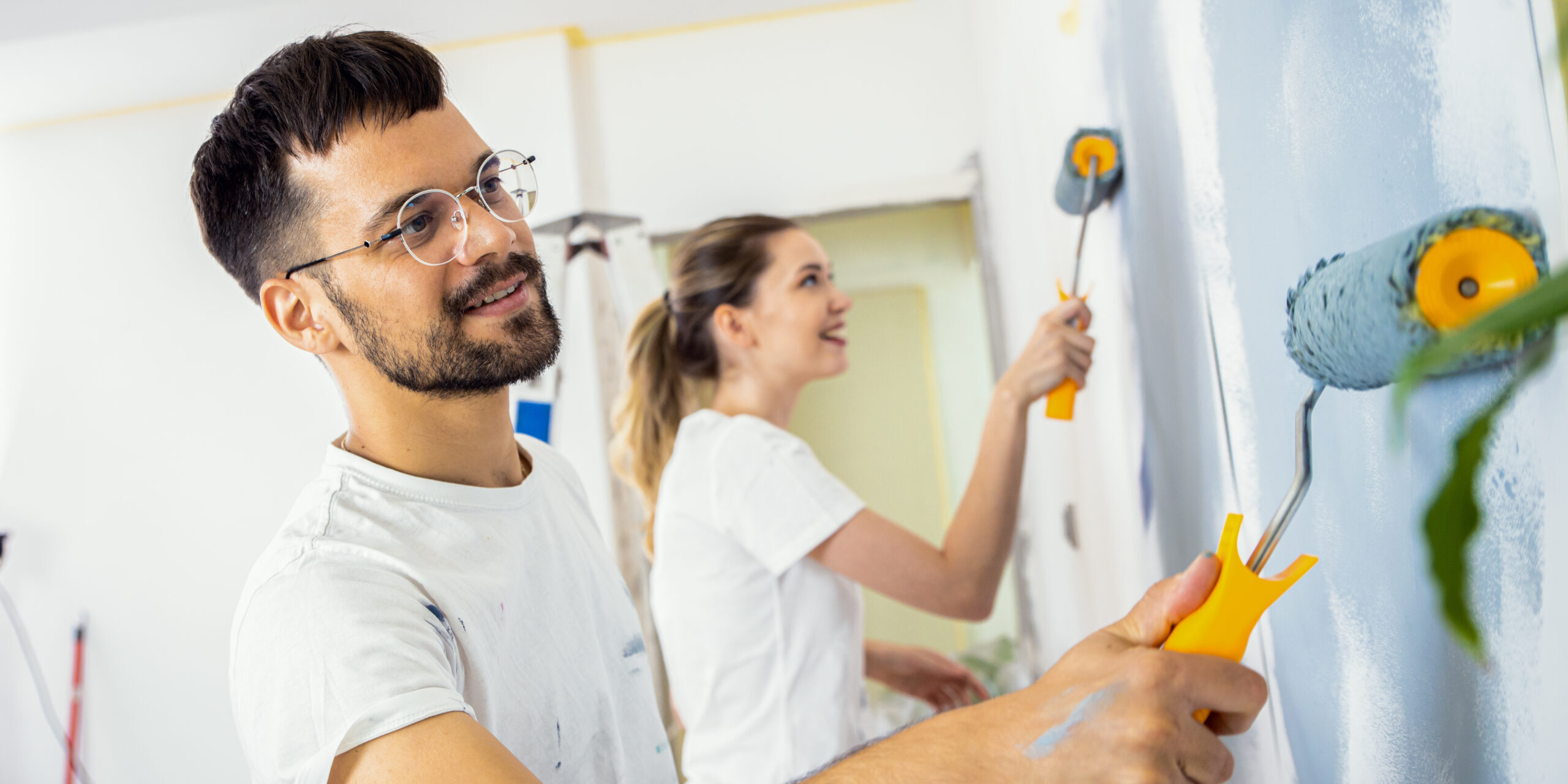 Smiling young couple painting wall in their home. Home Equity Loan
