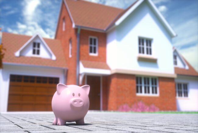 Pink piggy bank in front of a two-story brick home, representing home equity savings