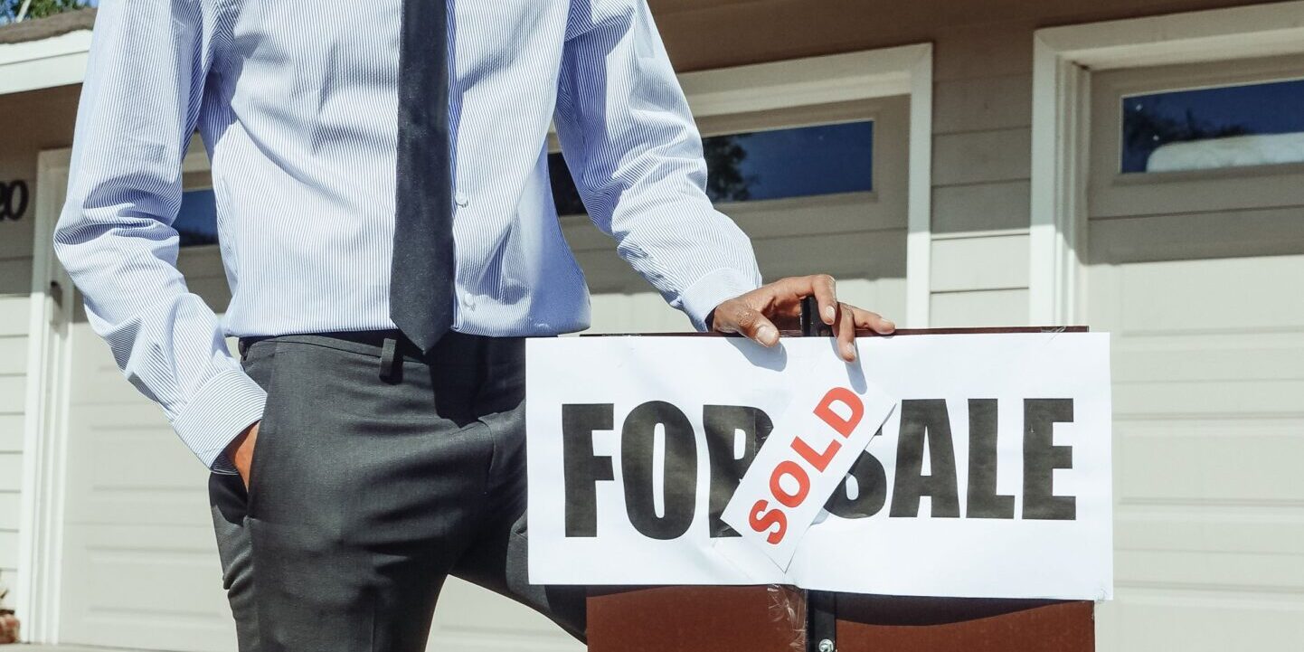 California real estate investor with sold sign – DSCR loans hero California real estate investor closing on an investment property using DSCR financing