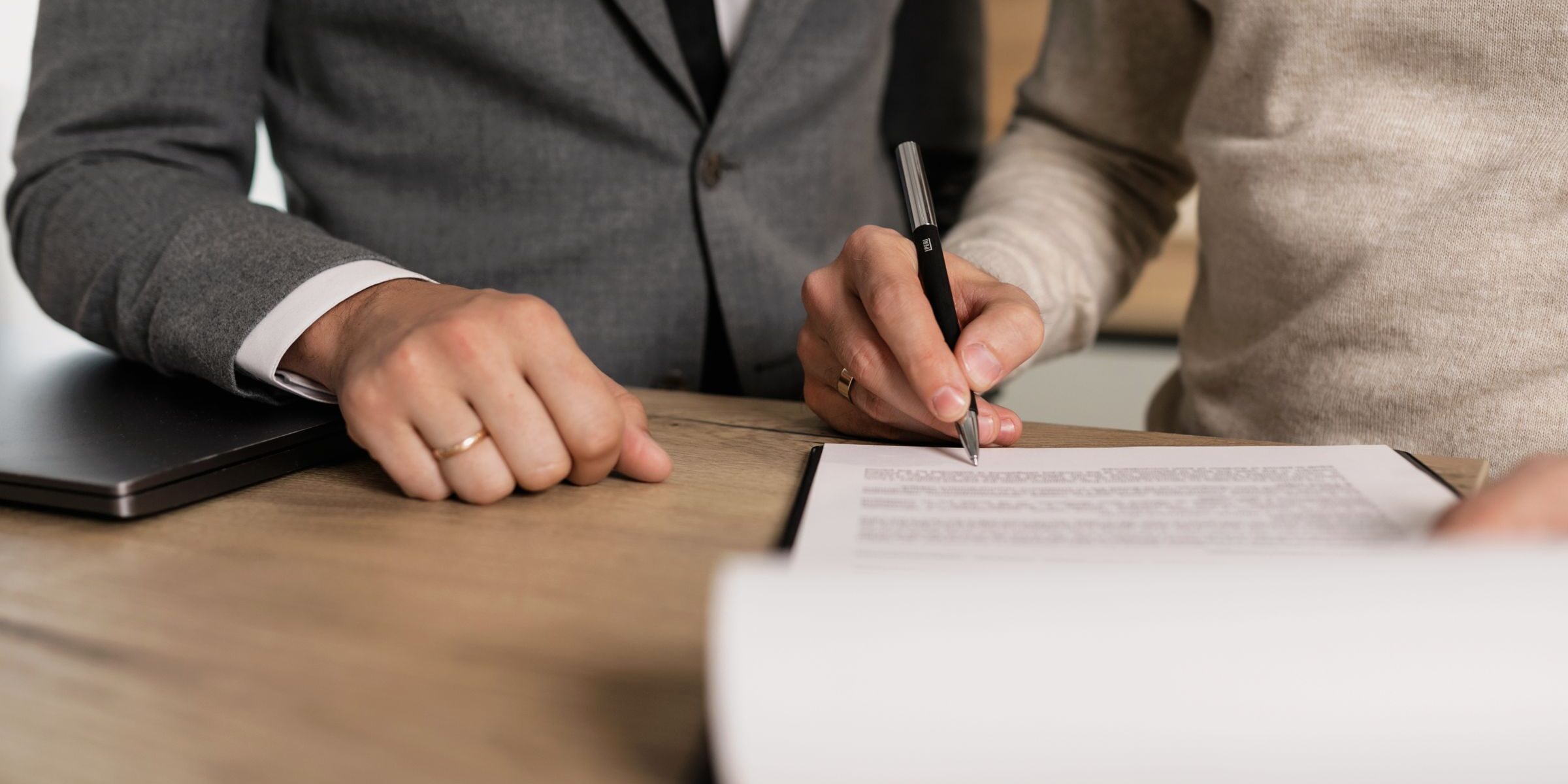 Couple signing closing documents at a desk with their broker