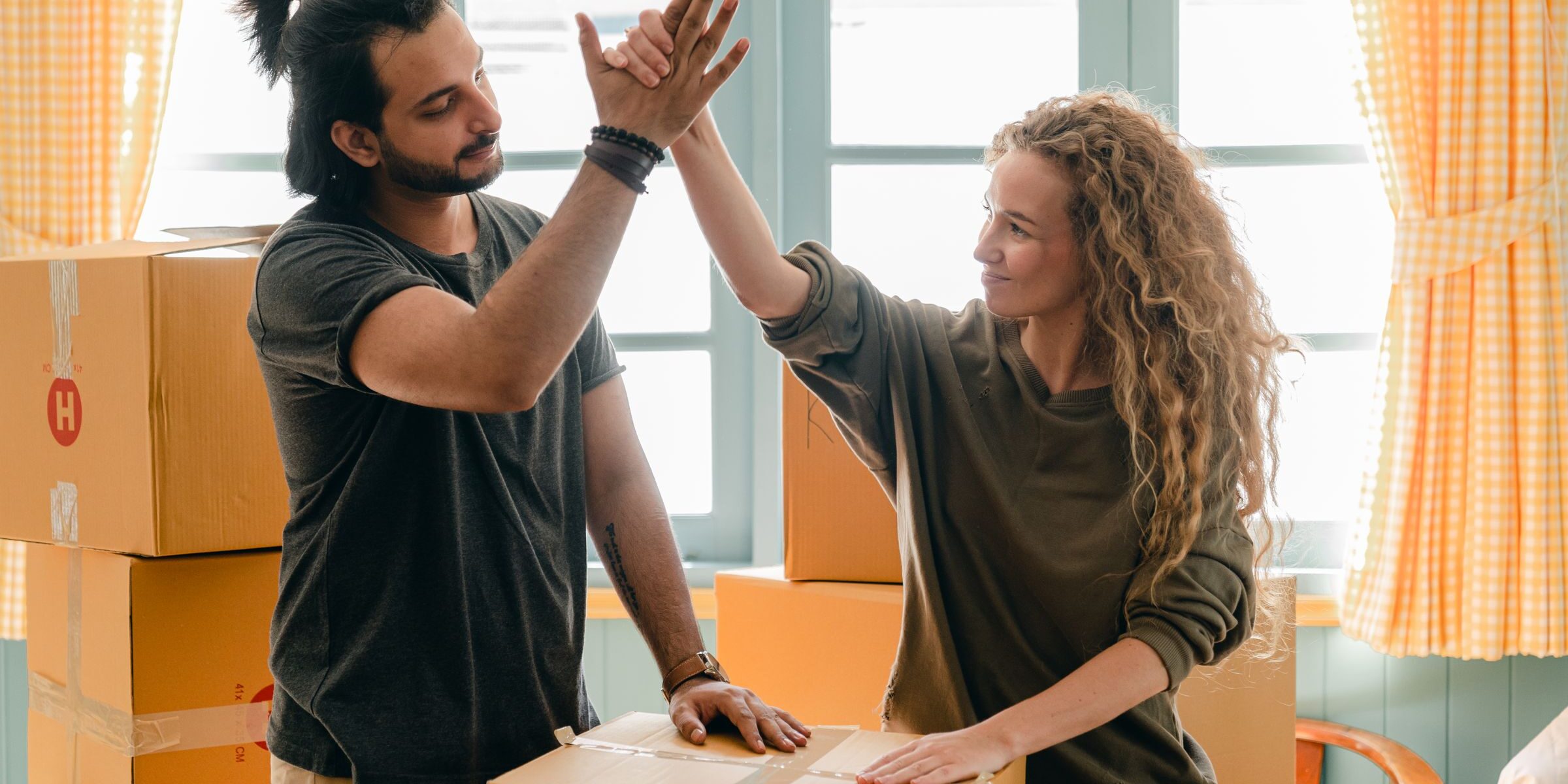 Couple high-fiving over moving boxes — celebrating their move to a new home