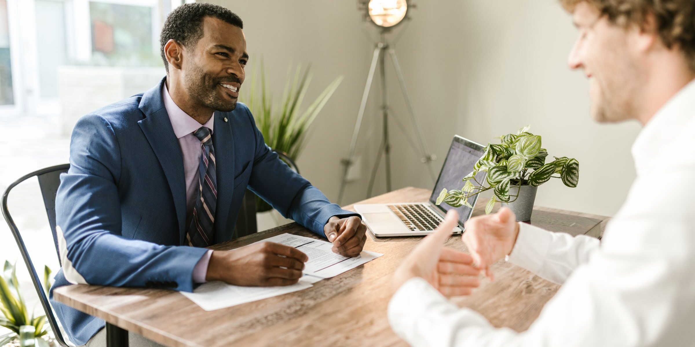 Mortgage broker reviewing refinance options with a client at a desk