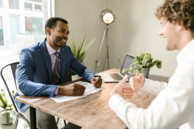 Mortgage broker reviewing refinance options with a client at a desk