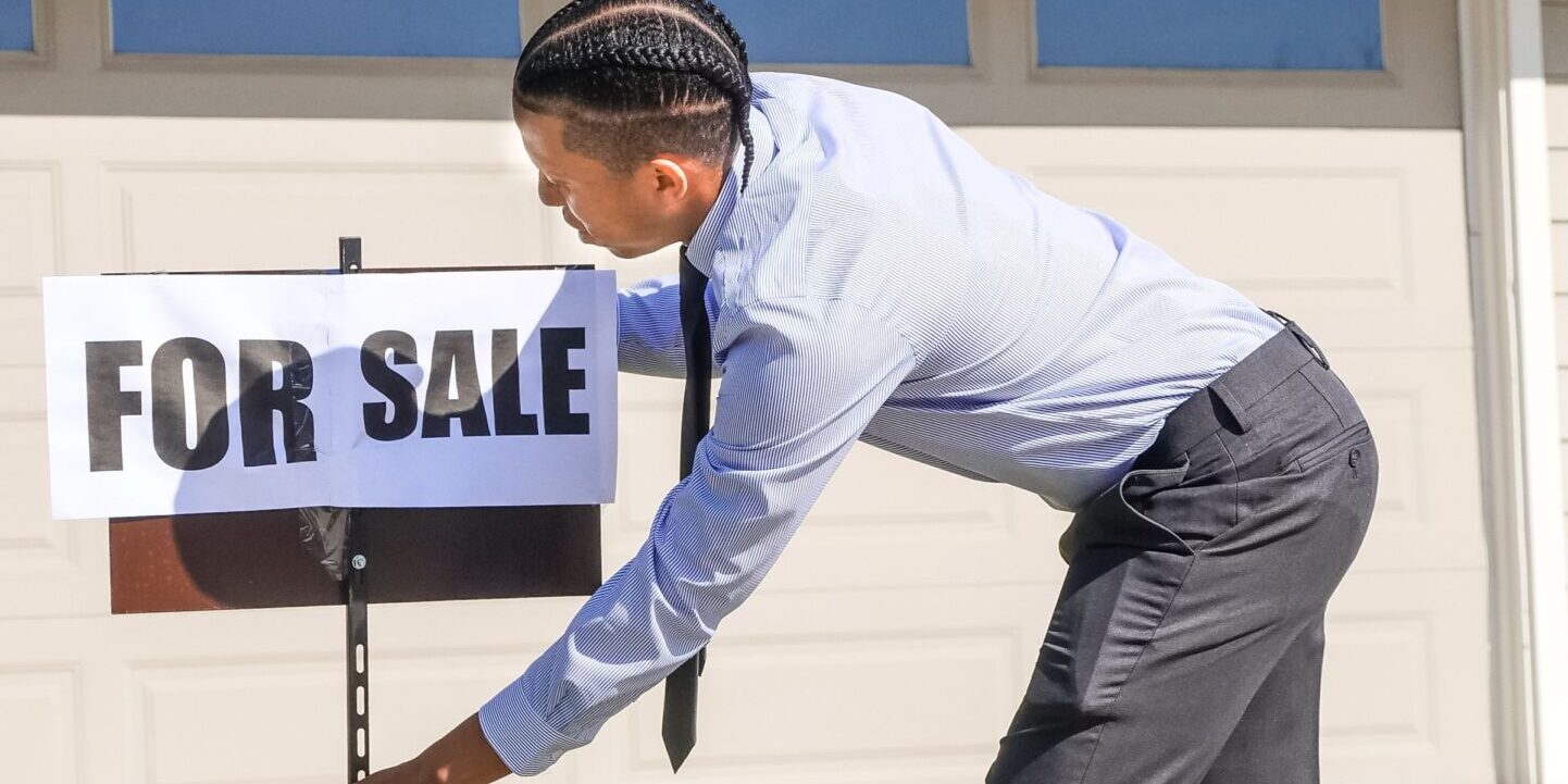 Texas real estate agent with for-sale sign – 1099 mortgage hero Texas real estate agent installing a for-sale sign at a suburban home