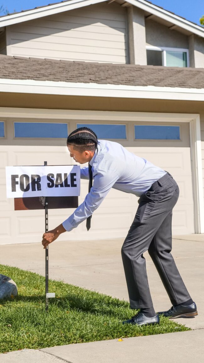 Texas real estate agent installing a for-sale sign at a suburban home