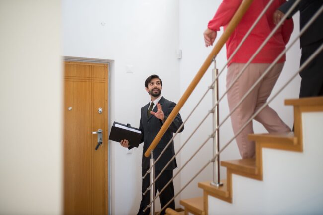 Virginia real estate agent leading buyers through staircase in modern home