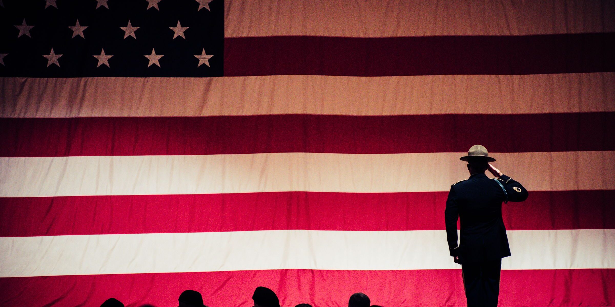 Soldier in dress uniform saluting the American flag