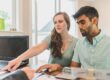 Young couple reviewing home buying strategy documents with financial advisor, planning smart approach in the current high-rate environment
