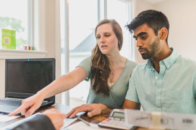 Young couple reviewing home buying strategy documents with financial advisor, planning smart approach in the current high-rate environment
