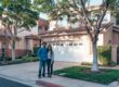 Smiling California couple standing proudly in front of their home, contemplating how to use their built-up equity through a HELOC