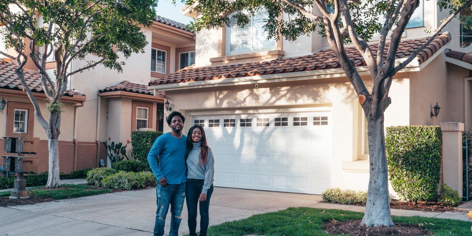 Couple in Front of Their Home – HELOC Equity Smiling California couple standing proudly in front of their home, contemplating how to use their built-up equity through a HELOC