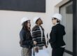 Real estate investors reviewing property plans on-site, evaluating a potential DSCR loan-financed rental property acquisition