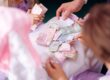 Family hands sorting money together, representing the mix of personal savings and family gift funds that first-time home buyers use for down payment in 2026