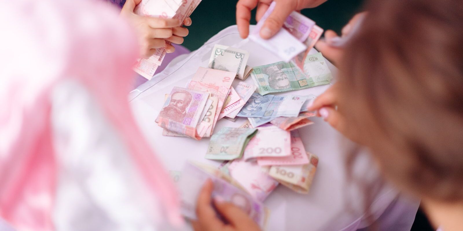Family Down Payment Savings Family hands sorting money together, representing the mix of personal savings and family gift funds that first-time home buyers use for down payment in 2026