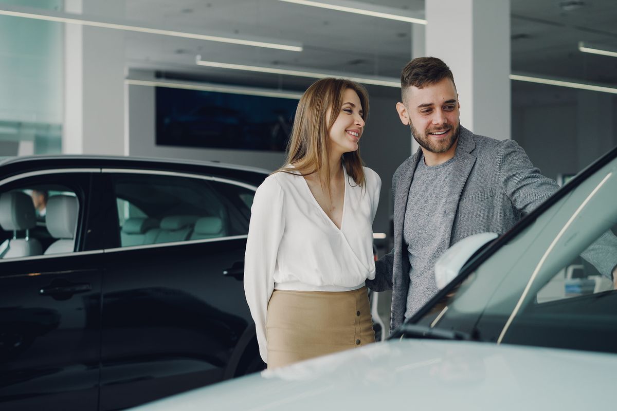Couple choosing a new car at a dealership, funding the purchase or paying off a high-rate auto loan with a home equity line of credit