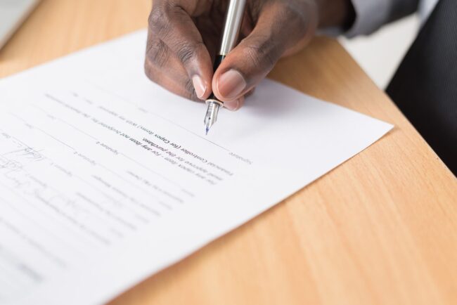Pen poised over mortgage document, representing the rate lock decision facing buyers and refinancers ahead of the September 15-16 FOMC meeting