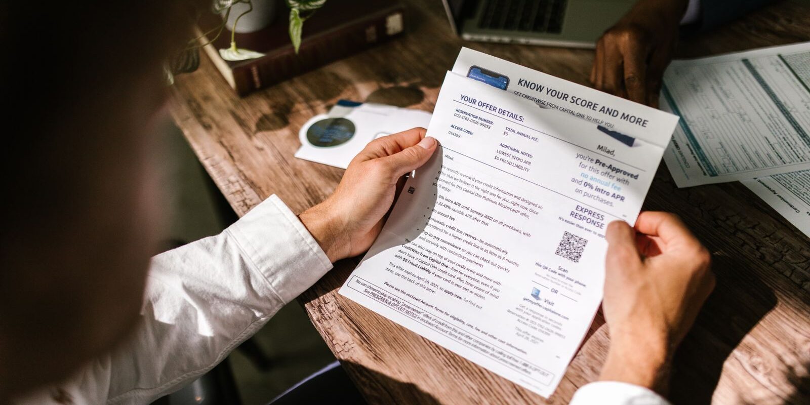 heloc-cashout-heloan-comparison-2026 Homeowner reviewing financial paperwork at a wooden desk under natural light, weighing the tradeoffs between a HELOC, a home equity loan, and a cash-out refinance in the higher-for-longer mortgage rate environment of September 2026