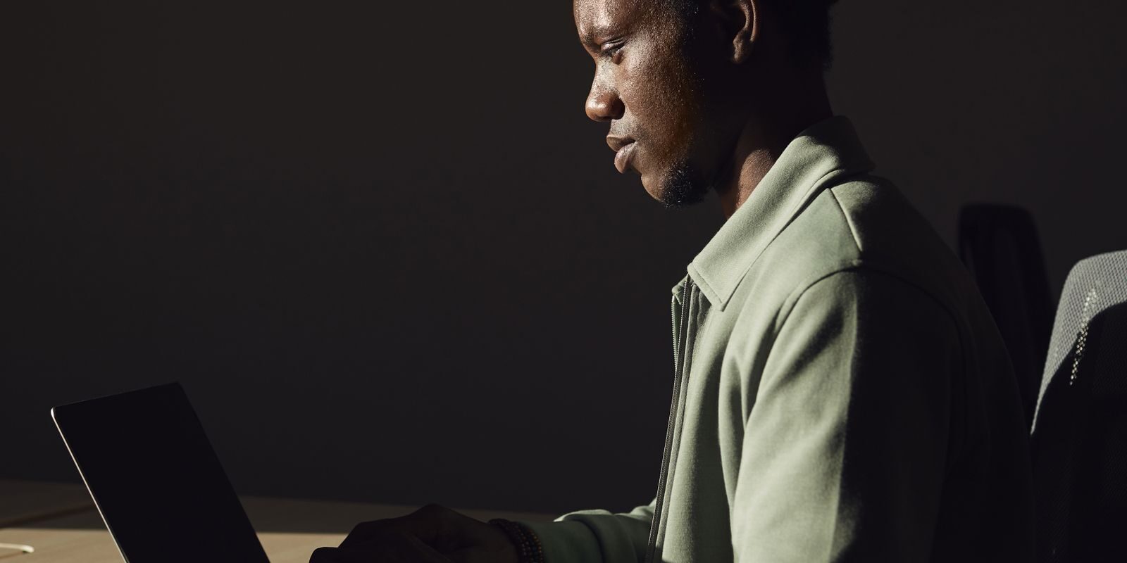 lock-vs-float-fed-decision-2026-v3 Professional deeply focused on his laptop in profile view, running the lock vs float mortgage rate decision math 48 hours before the September 16 FOMC decision under Federal Reserve Chair Kevin Warsh
