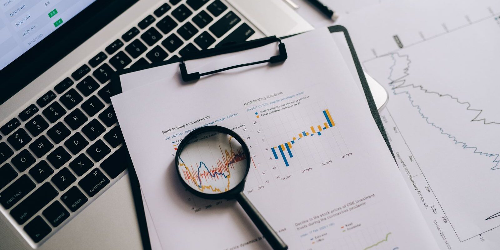 Overhead view of financial charts on paper with a laptop, magnifying glass, and analysis tools, previewing the September 2026 BLS Employment Situation Report ahead of Friday October 2 and its likely impact on mortgage rates