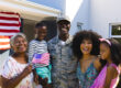 Multi-generational veteran family celebrating in front of their home with American flag draped from the porch, representing the veteran families OnPoint serves with the VA IRRRL refinance program