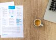 Resume, coffee, and laptop on a desk representing employment history review for mortgage qualification